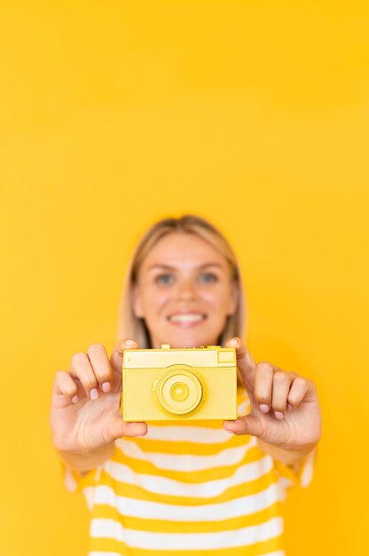 Medium shot woman holding yellow camera