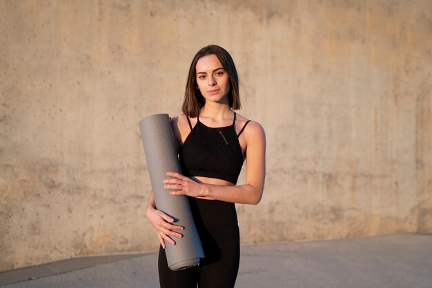 Женщина среднего роста с ковриком для йоги