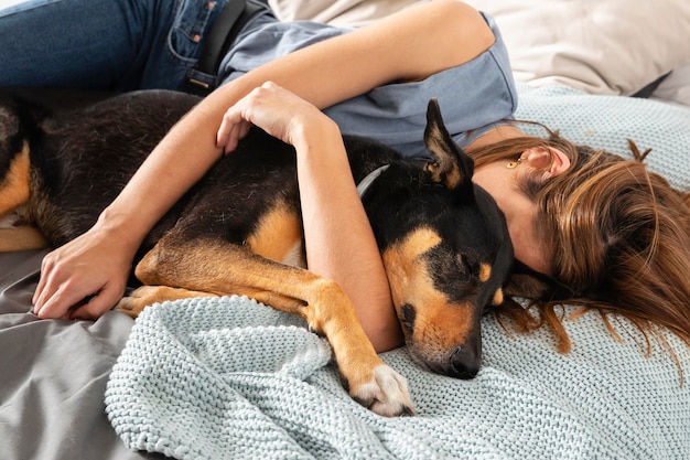 Medium shot woman hugging dog in bed