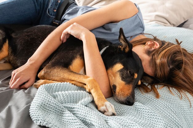 Женщина среднего выстрела обнимает собаку в постели
