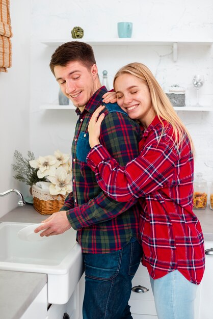 Medium shot woman hugging man in the kitchen