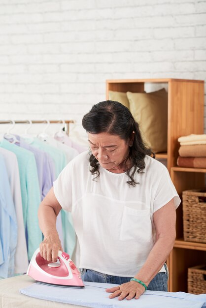 自宅で服をアイロンの女性のミディアムショット