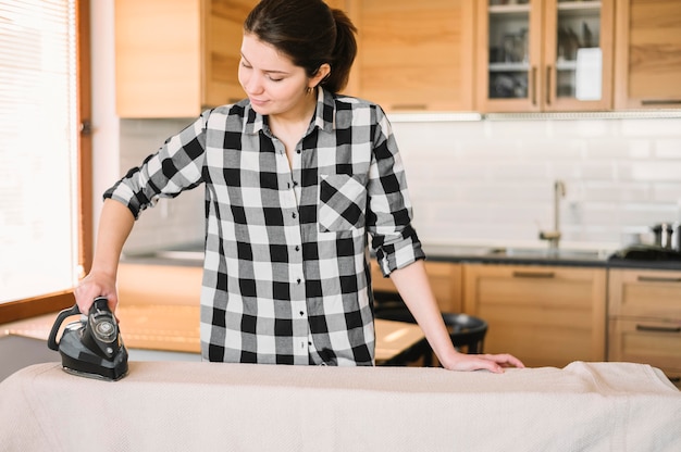 Free photo medium shot woman ironing towel