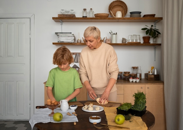 ミディアムショットの女性と子供が食べ物を準備する