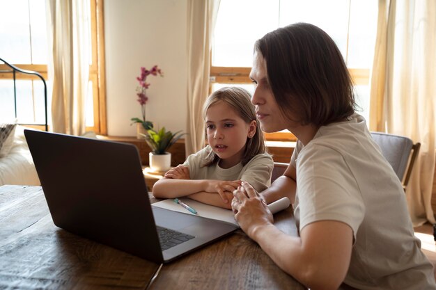 Medium shot woman and kid with laptop