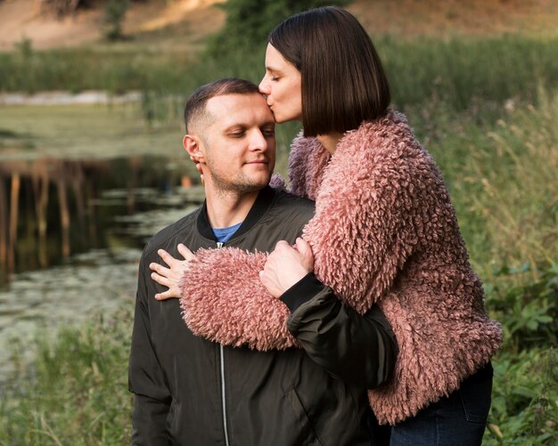 Free photo medium shot woman kissing boyfriend