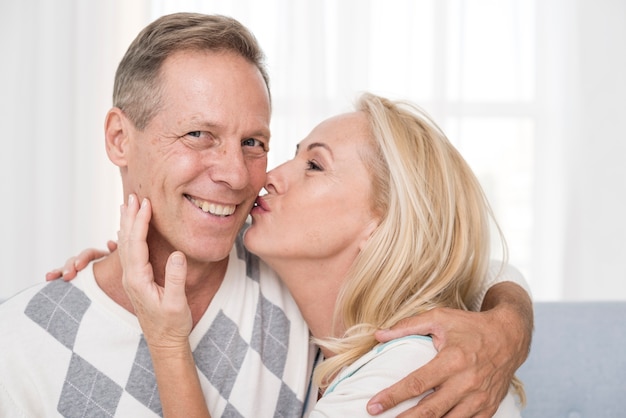 Medium shot woman kissing man on the cheek