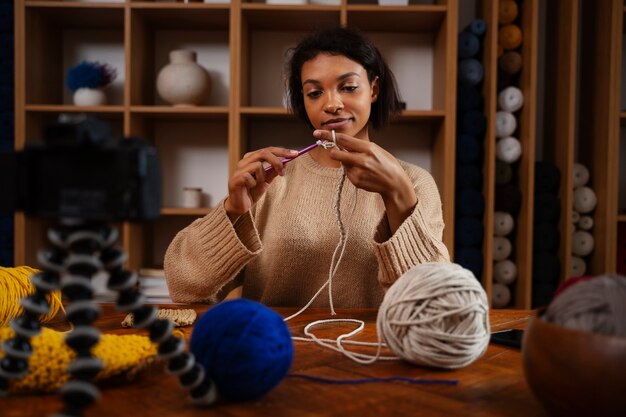 Medium shot woman knitting on camera