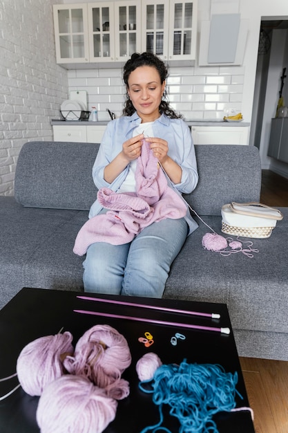 Free photo medium shot woman knitting on couch