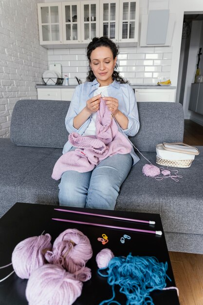 Medium shot woman knitting on couch