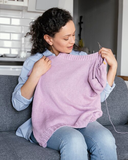 Medium shot woman knitting at home