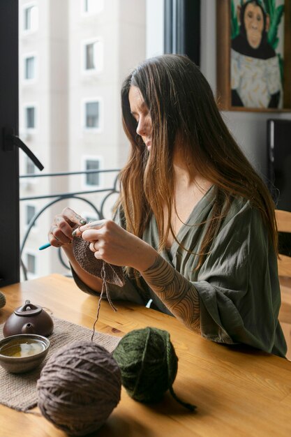 Medium shot woman knitting at home