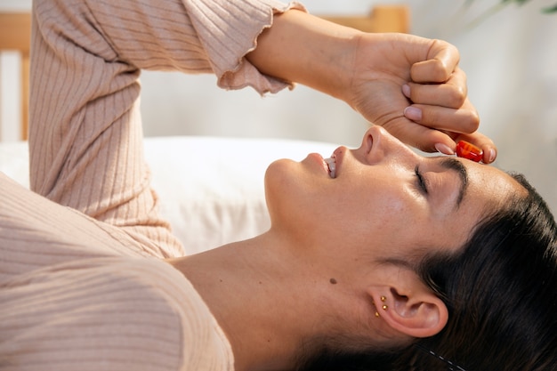 Medium shot woman laying in bed with crystal