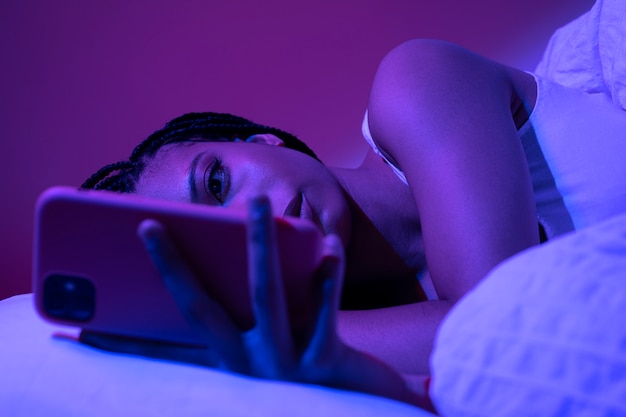 Medium shot woman laying with smartphone