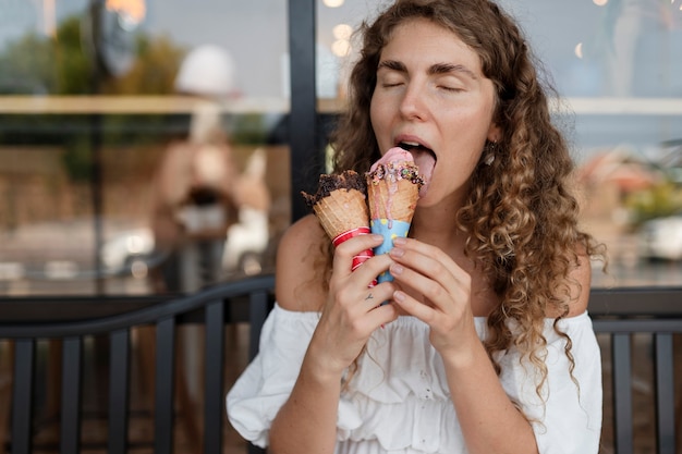 Женщина среднего выстрела лижет рожок мороженого