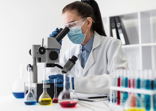 Medium shot woman looking through microscope