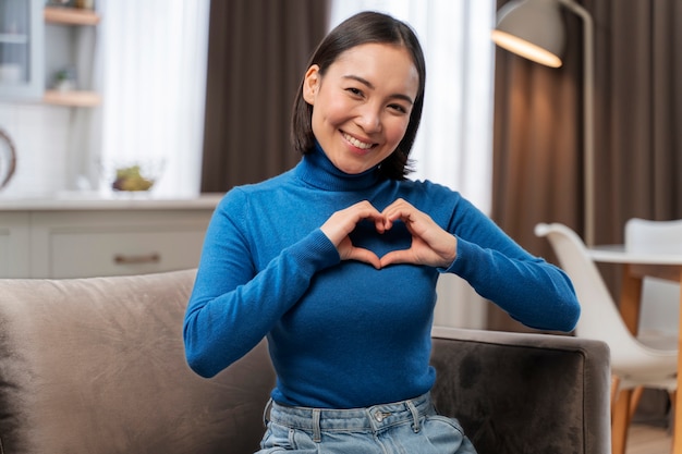 Free photo medium shot woman making heart shape