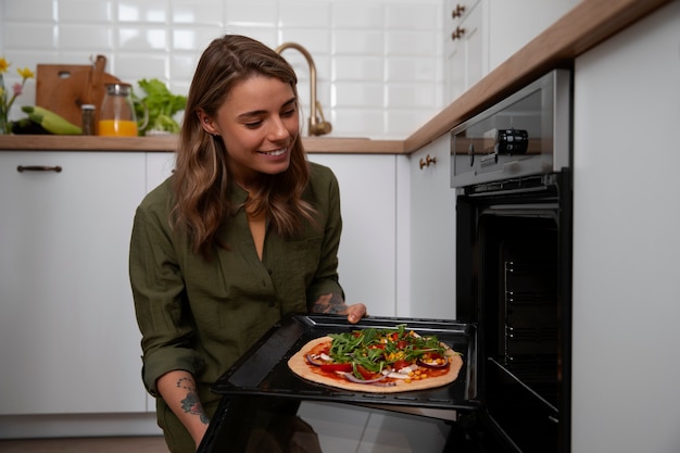 Бесплатное фото Женщина среднего роста готовит пиццу