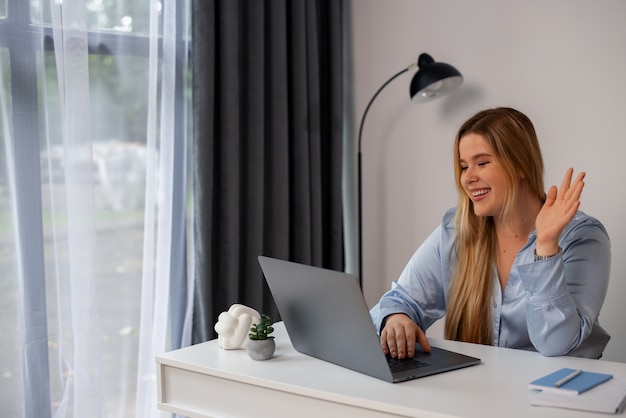 Foto gratuita donna del piano medio che effettua videochiamate con il laptop