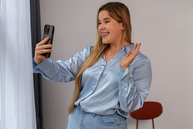 Free photo medium shot woman making video calls with smartphone