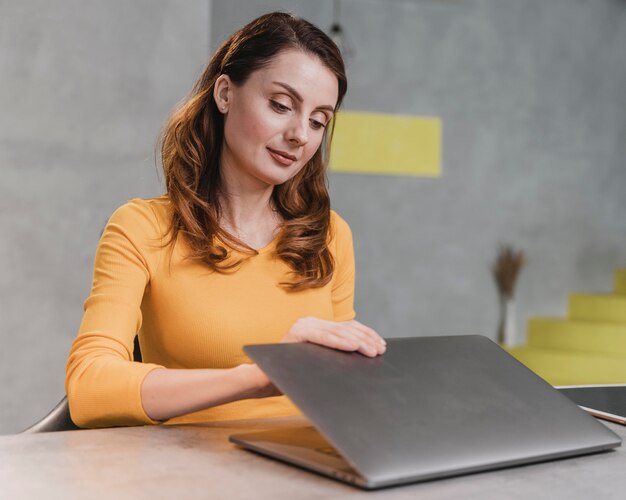 Medium shot woman opening laptop