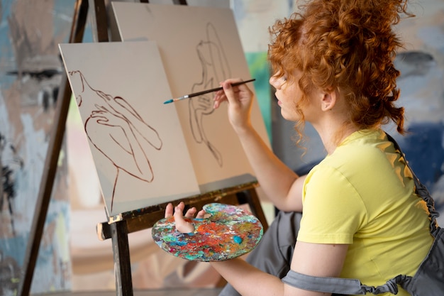 Medium shot woman painting on canvas