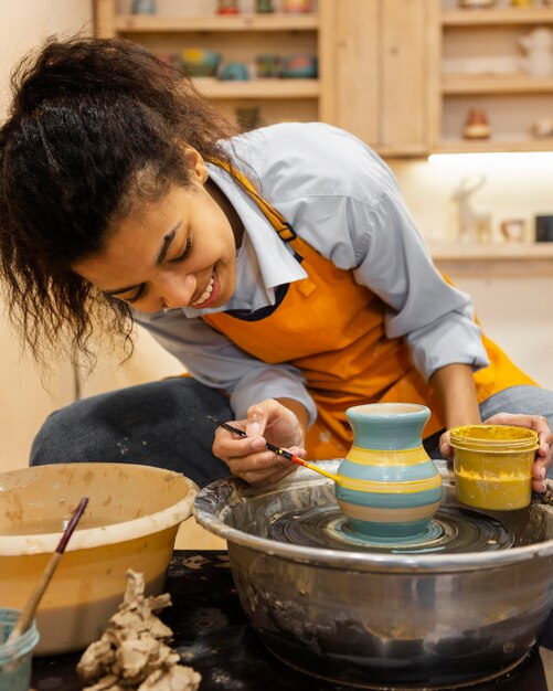 Medium shot woman painting clay pot