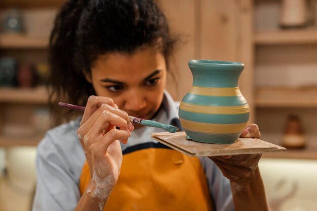Medium shot woman painting pot