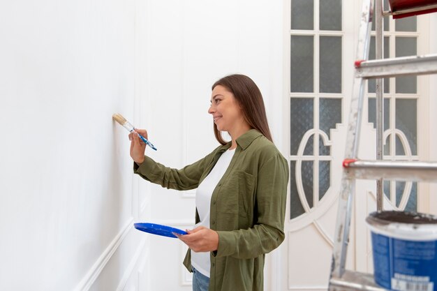 Средний снимок женщина рисует стену
