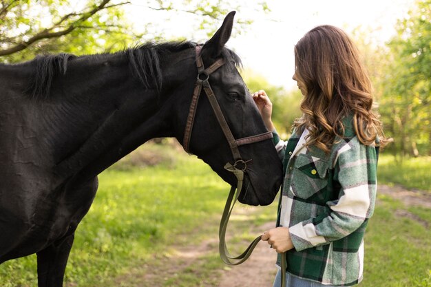 ミディアムショットの女性が馬をかわいがる