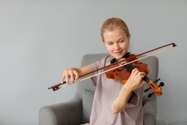 실내에서 바이올린을 연주하는 미디엄 샷 여성