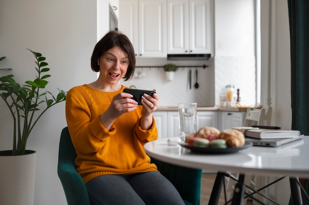 Medium shot woman playing with her phone