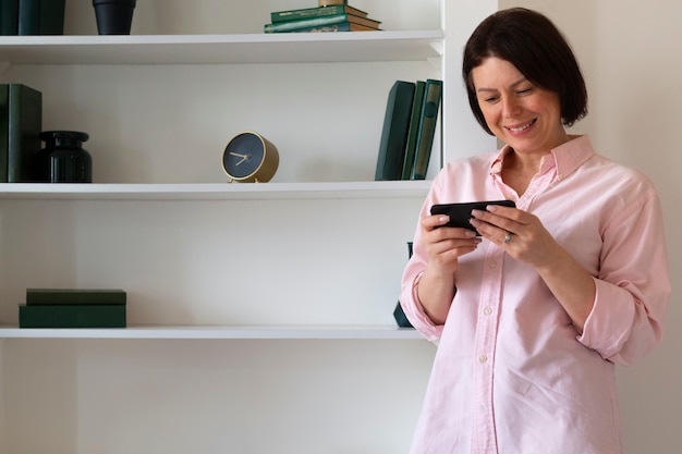 Medium shot woman playing with her phone