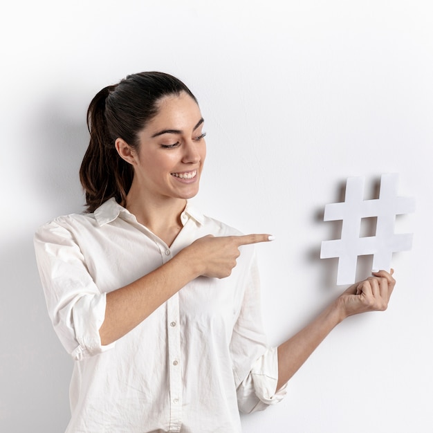 Medium shot woman pointing at hashtag object