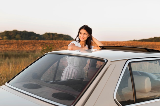 Medium shot woman posing near car