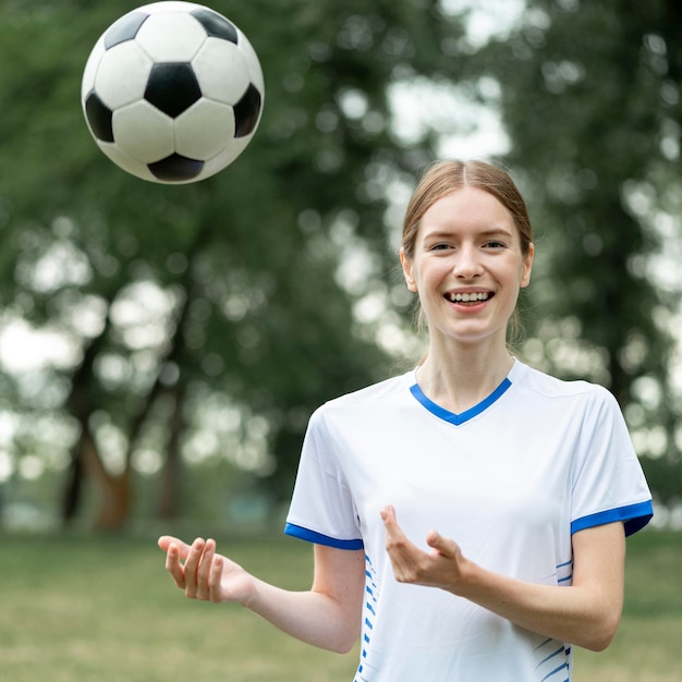 Бесплатное фото Среднего выстрела женщина позирует с мячом