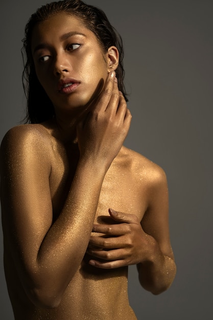 Medium shot woman posing with gold body painting