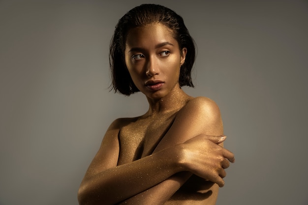 Medium shot woman posing with gold body painting