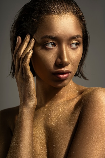 Medium shot woman posing with gold body painting