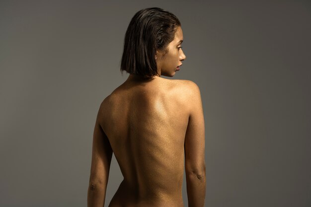 Medium shot woman posing with gold body painting