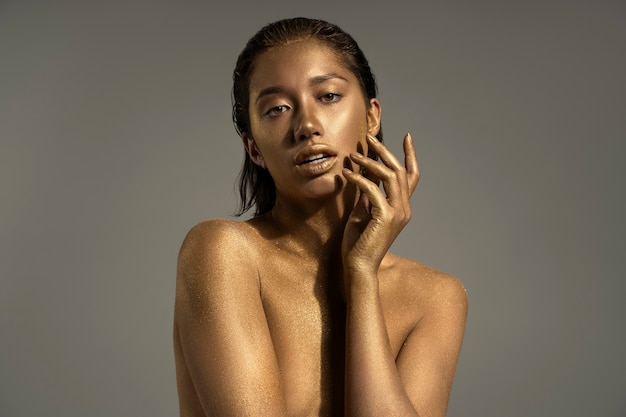 Medium shot woman posing with gold body painting