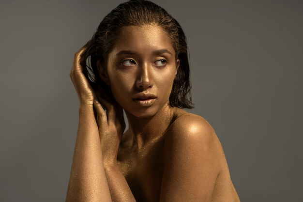 Medium shot woman posing with gold body painting