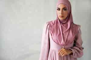 Foto gratuita donna del colpo medio che posa con l'hijab rosa