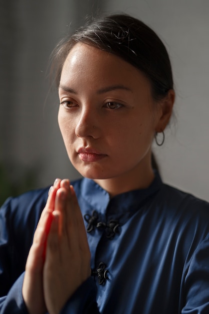 Foto gratuita donna del colpo medio che pratica il tai chi al chiuso