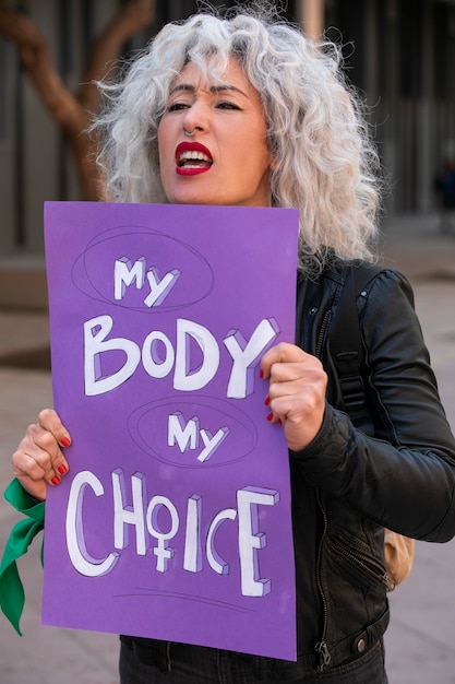 Бесплатное фото Женщина среднего роста протестует на улице