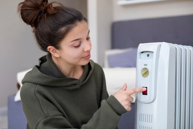 Free photo medium shot woman pushing on heater's red button