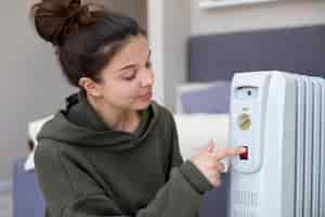 Foto gratuita donna del colpo medio che spinge sul pulsante rosso del riscaldatore