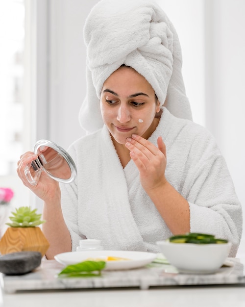 Medium shot woman putting on cream