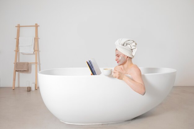 욕조에서 독서를 하는 미디엄 샷 여성