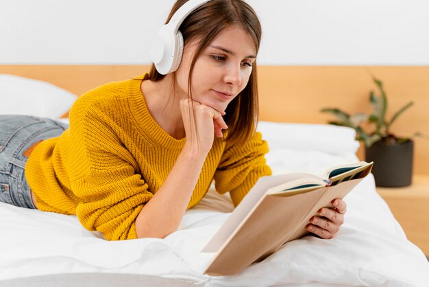 Free photo medium shot woman reading in bed